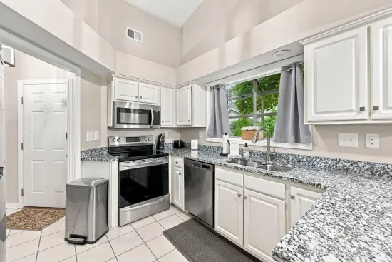 Bright kitchen with granite counters, stainless appliances & vaulted ceilings