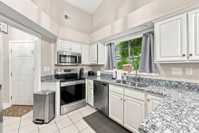 Bright kitchen with granite counters, stainless appliances & vaulted ceilings