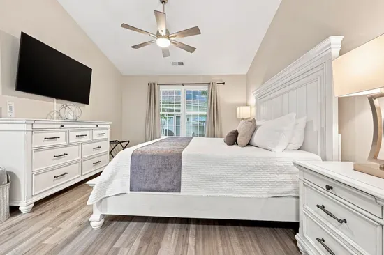 Bright king bedroom with elegant furnishings, TV, and natural light