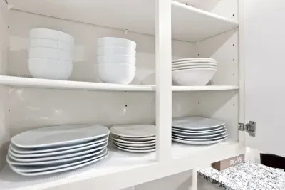 Well-stocked kitchen cabinet with neatly organized matching dinnerware