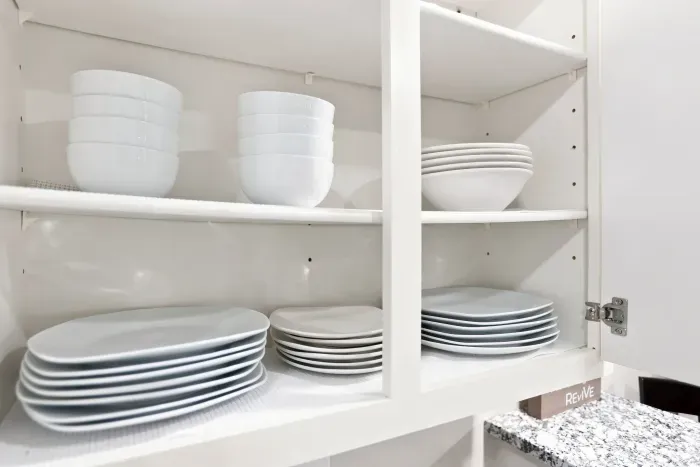 Well-stocked kitchen cabinet with neatly organized matching dinnerware