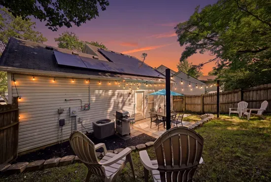 Cozy fenced backyard with string lights, grill, and sunset patio seating