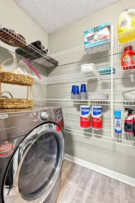 Fully stocked laundry room with washer, storage shelves, and guest essentials