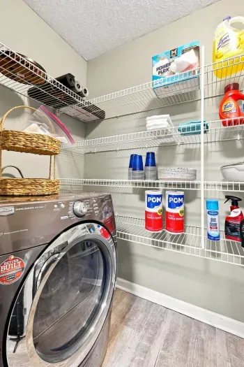 Fully stocked laundry room with washer, storage shelves, and guest essentials