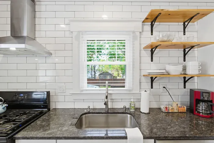 Bright modern kitchen with subway tile, open shelving, and sunny window views