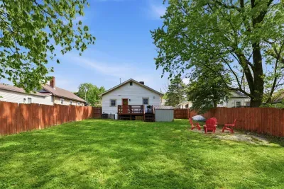 Spacious fenced backyard with deck, shade trees, and outdoor seating
