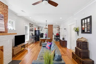 Bright open living space with hardwood floors and charming brick details