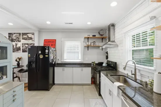 Bright modern kitchen with granite counters, gas range, and sunny windows