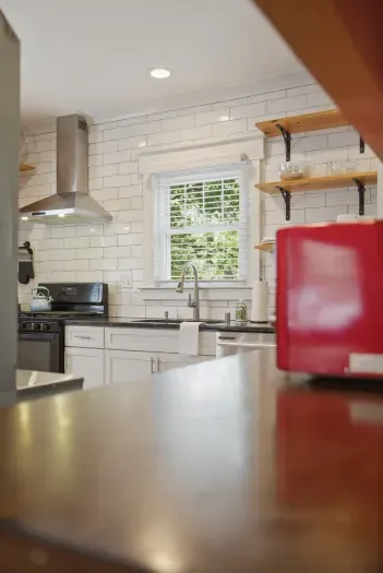 Bright modern kitchen with subway tile, open shelves, and natural light