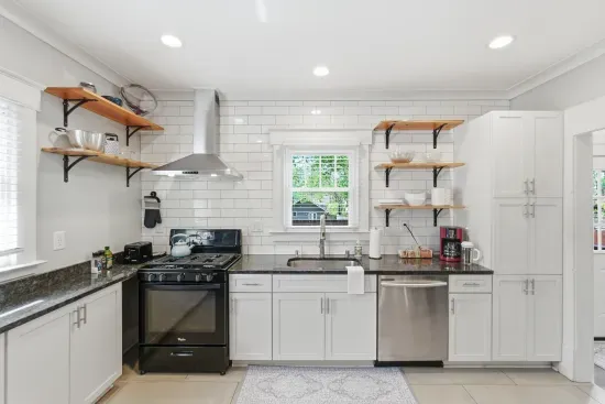 Bright modern kitchen with subway tile, open shelves, and stainless accents