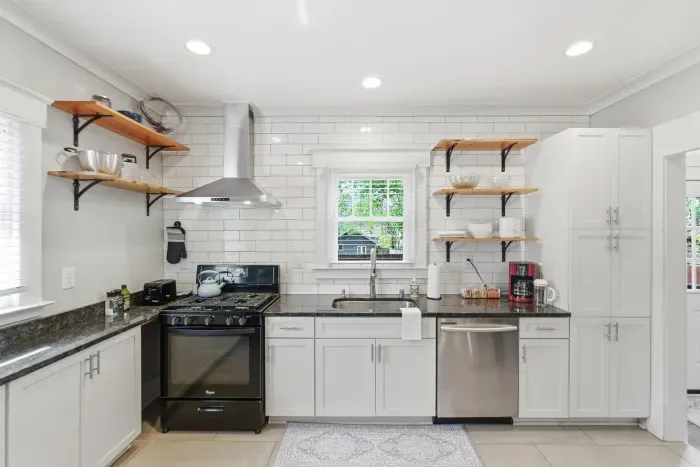 Bright modern kitchen with subway tile, open shelves, and stainless accents