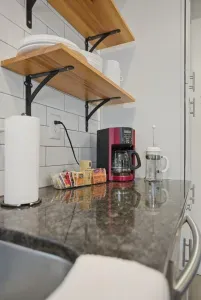 Modern kitchen coffee station with granite counters and open shelving