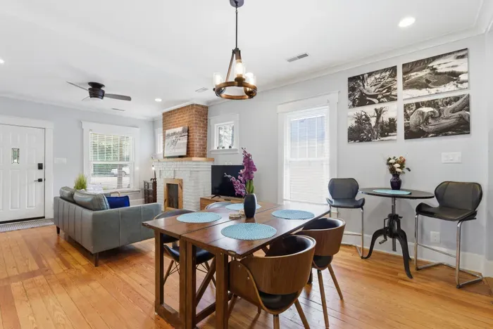 Bright open living space with hardwood floors, dining area, and brick fireplace