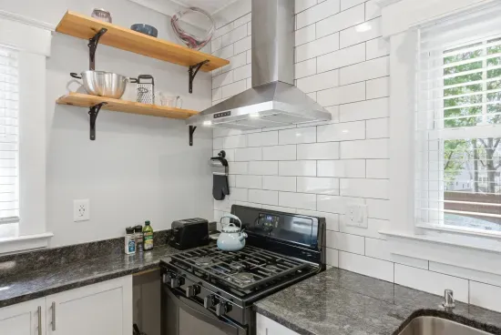 Bright modern kitchen with gas range, subway tile, and open shelving