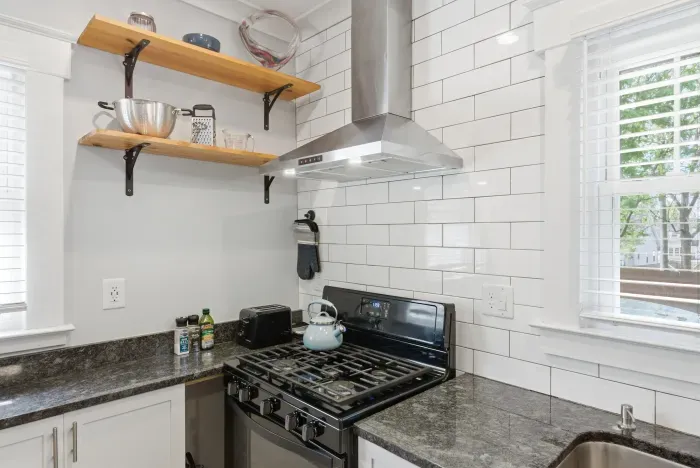 Bright modern kitchen with gas range, subway tile, and open shelving