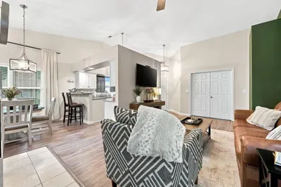 Bright open living space with vaulted ceilings, TV, dining area, and breakfast bar