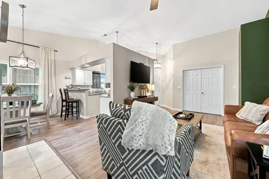 Bright open living space with vaulted ceilings, TV, dining area, and breakfast bar