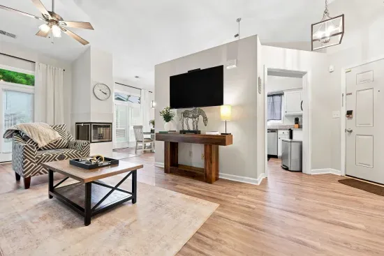 Bright open living room with fireplace, vaulted ceilings, and big TV
