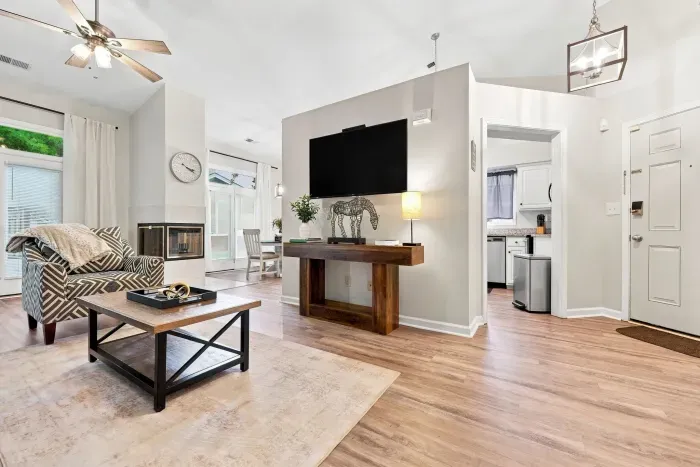 Bright open living room with fireplace, vaulted ceilings, and big TV