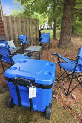 Shaded backyard hangout with camp chairs, table, and rolling cooler