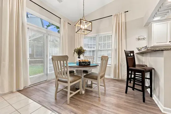 Bright dining nook with vaulted ceilings, patio access, and breakfast bar