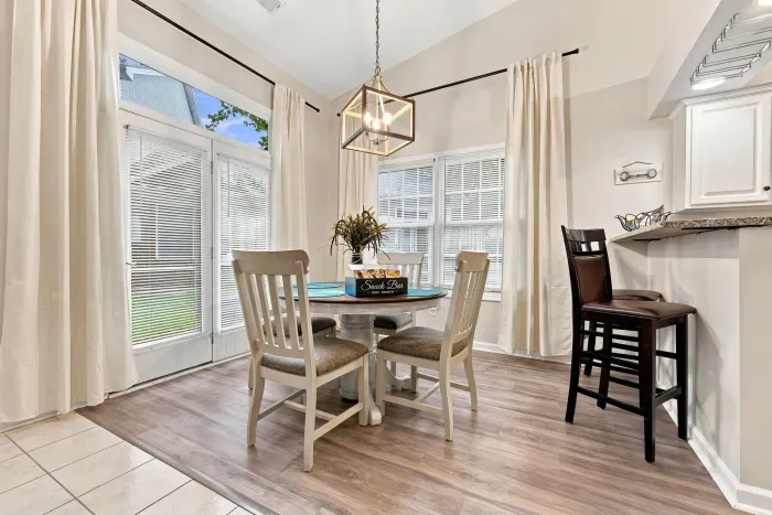 Bright dining nook with vaulted ceilings, patio access, and breakfast bar
