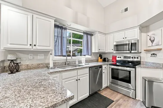 Bright vaulted kitchen with granite counters and stainless appliances