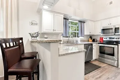 Bright kitchen with granite counters, stainless appliances, and bar seating