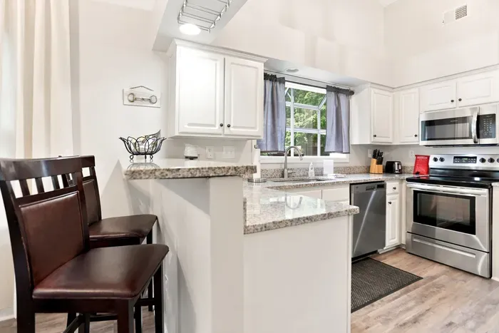 Bright kitchen with granite counters, stainless appliances, and bar seating