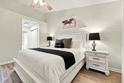 Bright, stylish bedroom with a plush bed, ceiling fan, and ensuite access