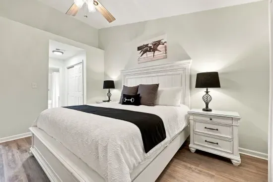 Bright, stylish bedroom with a plush bed, ceiling fan, and ensuite access