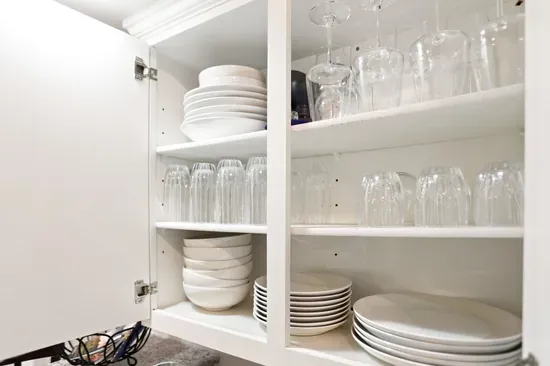 Well-stocked kitchen cabinet with organized dishes, glasses, and wineware