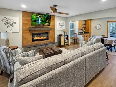 Cozy up by the fire. 🔥 This inviting living room features a sleek electric fireplace set against a beautiful wood accent wall. With a large sectional and a flat-screen TV, it’s the perfect hub for movie nights and group relaxation.