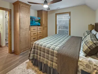 A cozy mountain nook. 🏔️ Retreat to this king suite featuring custom wood armoires, a flat-screen TV, and plush plaid bedding. It’s the perfect blend of rustic charm and modern convenience for a restful night’s sleep.