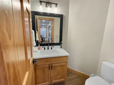 The perfect convenience for your group. ✨ This main-level half bath features a warm wood vanity and modern black hardware. It’s a stylish and practical addition that ensures comfort for everyone while hanging out in the common areas.