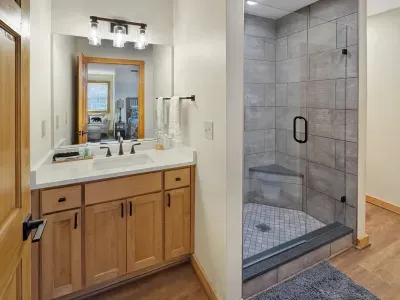 Privacy and comfort for every guest. 🚿 This sleek en-suite features a spacious walk-in shower with a convenient built-in bench and modern finishes. It’s one of four private bathrooms designed to make your group's stay effortless.