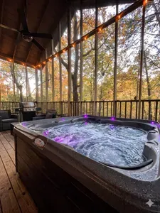 Sink into the screened-porch hot tub with the string lights on and the fall foliage glowing through the screen — soak in any weather, bug-free, glass of wine in hand. This is the longest exhale of your week.