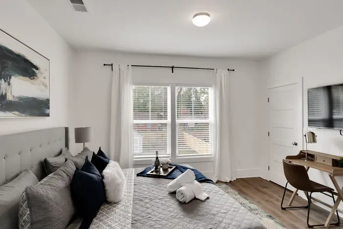 Modern and cozy bedroom featuring a plush queen bed, smart TV, dedicated workspace, and natural light — your perfect retreat after a day of exploring!