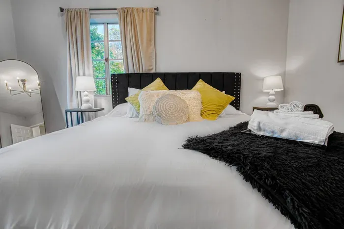 Bright, modern bedroom with a cozy bed, workspace by the window, and smart TV — designed for comfort and productivity.