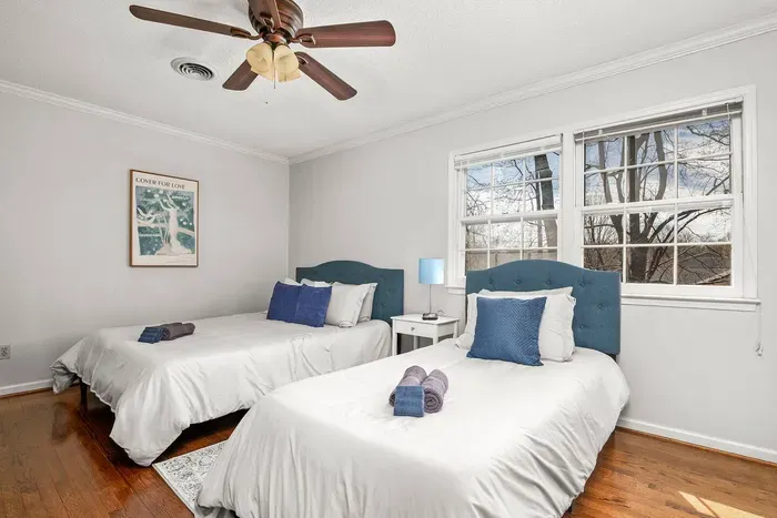 Cozy bedroom with one queen sized and one twin sized bed, two closets, and a 43-inch smart TV.