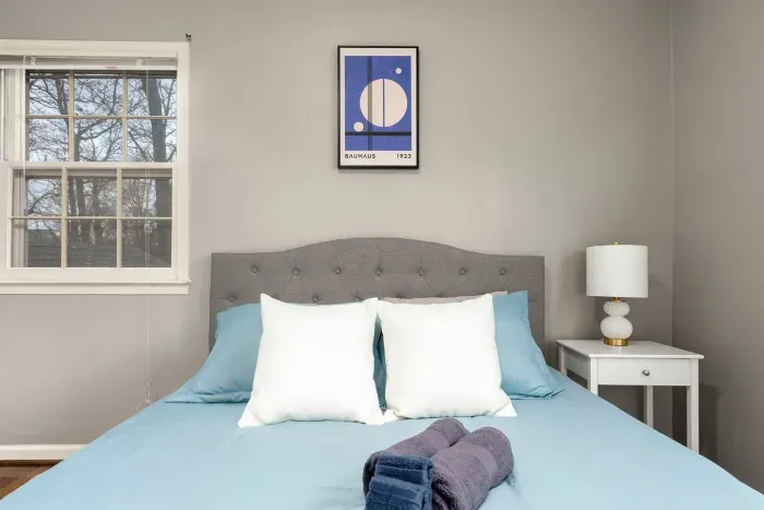 Bright airy bedroom with queen bed, two closets, plenty of pillows, dresser and nightstand.