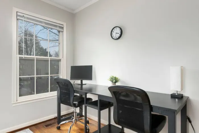 Two person desk with one monitor and adjustable chairs to sit down and get some work down.