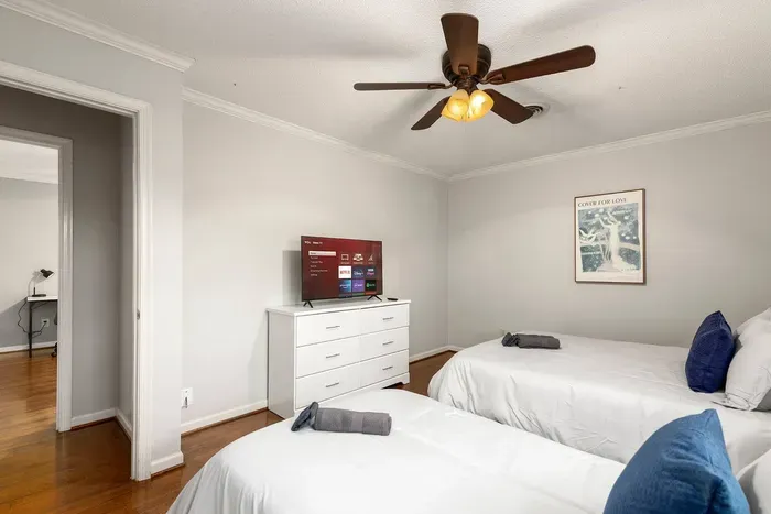 Cozy bedroom with one queen sized and one twin sized bed, two closets, and a 43-inch smart TV.