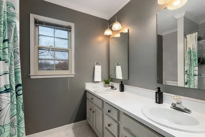 Upstairs bathroom with double vanity and stocked with body wash, shampoo, conditioner, hair dryer and towels.