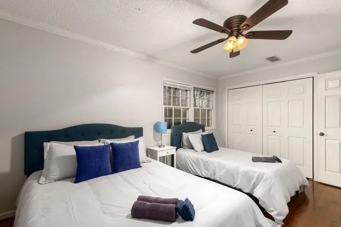 Cozy bedroom with one queen sized and one twin sized bed, two closets, and a 43-inch smart TV.
