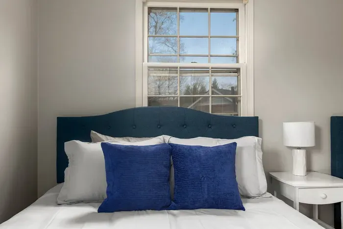 Cozy bedroom with two queen sized beds, plenty of pillows, two closets, and a nightstand with storage.