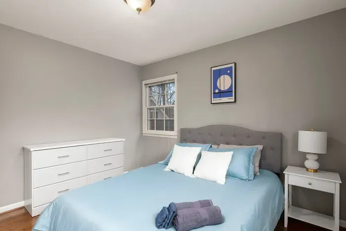 Bright airy bedroom with queen bed, two closets, plenty of pillows, dresser and nightstand.