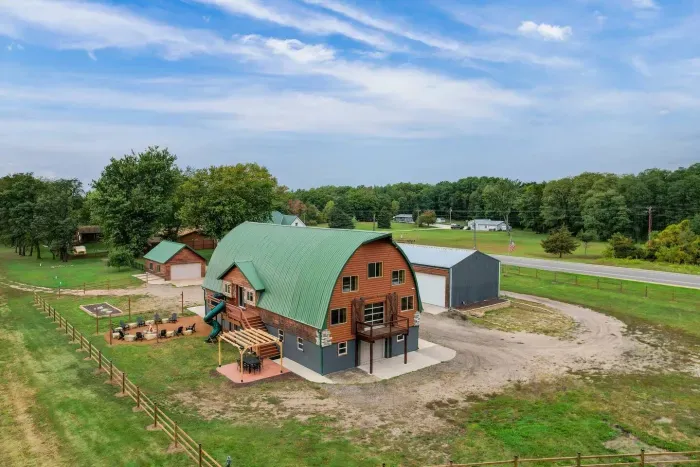 Outdoor dining area under a pergola with string lights, next to the fire pit and slide