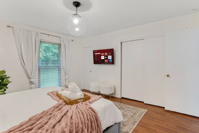 The door to the left of the TV leads to the master bathroom. The closet to the right of the TV has been provided with hangers and ample area for storage. 