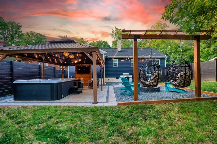 Another view of our one of a kind private backyard oasis with a large gazebo covering hot tub, patio furniture and Smart TV. Next to it is our fire pit surrounded by swing chairs, Adirondack chairs and a 5-burner gas grill. 